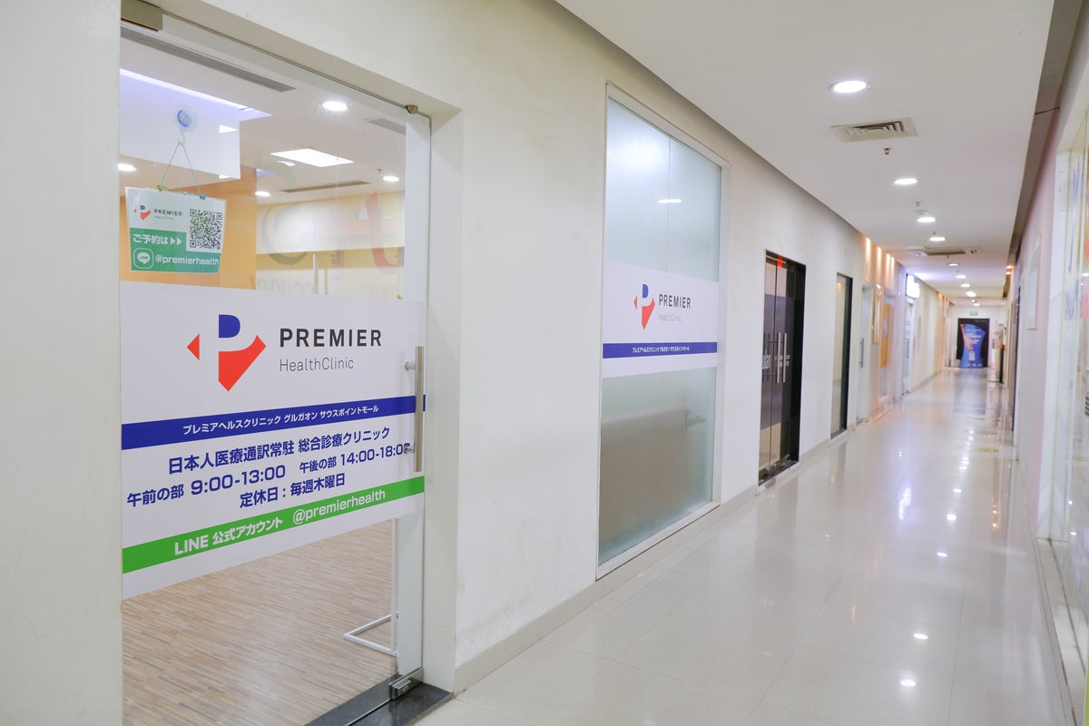 Premier HealthClinicのガラス戸の入り口。クリニック名と診療時間が表示されている。