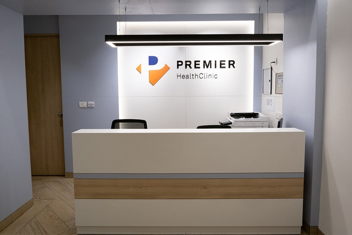 清潔感のある白い受付カウンターと、その奥に「PREMIER Health Clinic」のロゴが見える。